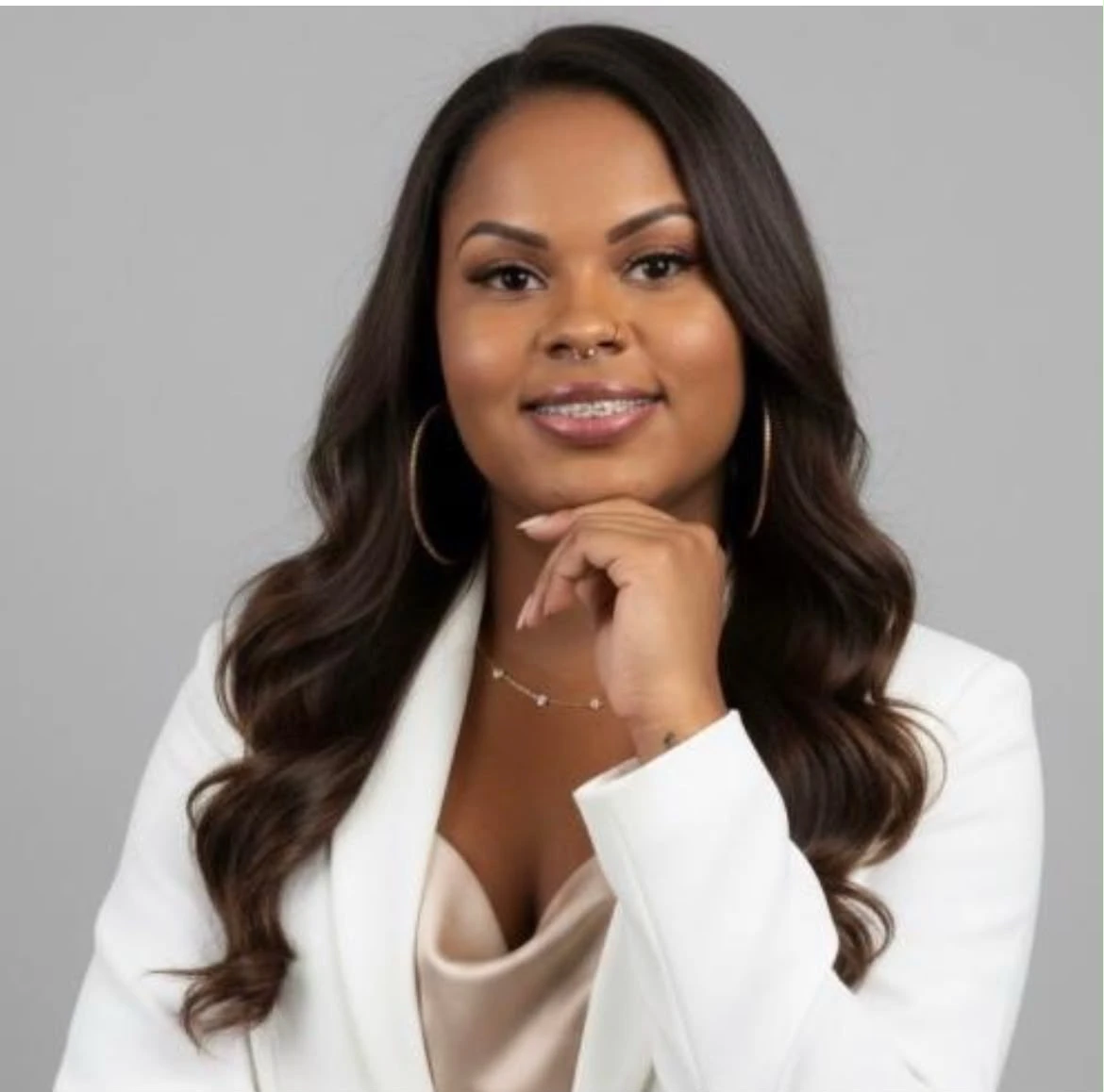 Profissional da Divas Beauty sorrindo, de blazer branco